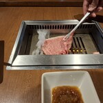 焼肉うしごろ - 2枚目の佐賀県産の大判サーロインを、網の鉄板の上で焼いている様子・その1です。