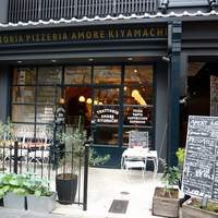 アモーレ 木屋町 - １階部分です。ここだけ見ると洒落たカフェにも見えますね。店内の照明器具がいい感じで輝いています。店前には緑が沢山ありますよ。お洒落なテーブルも出ていますね。