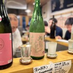 田っくんのサテライト商店 - まずはそれぞれ好みの日本酒を、番号でオーダー。
                                キッチンを中心とした、
                                コの字型カウンターで注いでもらった日本酒受け取り…
                                血の一滴を溢さぬよう！
                                自分の席へ運びます。