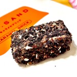 ニューヨークシティサンド - 蜂蜜で炊き上げたキャラメルヌガーにローストアーモンド、ミルクチョコ、ブラッククランチとココナッツを使用