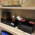 資さんうどん - 容器にはとろろ昆布と天かすが入っていて入れ放題だが、無料だからといって沢山入れると、せっかくの美味いダシが台無しになる