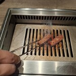 焼肉うしごろ - 熊本県産のA5厚切りサーロインを、網の鉄板の上で焼いている様子のその3です。