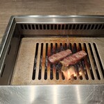 焼肉うしごろ - 熊本県産のA5厚切りサーロインを、網の鉄板の上で焼いている様子のその7です。