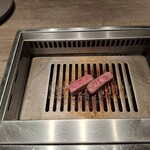 焼肉うしごろ - 熊本県産のA5厚切りサーロインを、網の鉄板の上で焼いている様子のその4です。