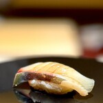 くるますし - シマアジ。 炭で炙ったり、湯煎したり、蒸籠で蒸したり、まったくいろいろやらかしてくれる大将ですが、これは正統な江戸前鮨。 タネの下に仕込まれた香りの爆弾が弾けてなんという爽快な鮨。 シマアジ、旨〜。