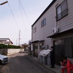 吉本食品 - 右の建物が店舗、左手の空き地と路地の奥が駐車場