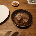 焼肉うしごろ - 網の鉄板で焼いた鹿児島県産の大判サーロインを、ハサミで半分に切ってポン酢に入れた様子のその1です。