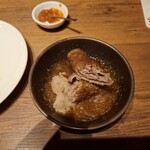 焼肉うしごろ - 網の鉄板で焼いた鹿児島県産の大判サーロインを、ハサミで半分に切ってポン酢に入れた様子のその2です。