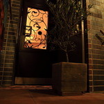 BRILLANTE IL SUZUKI - 階段を上り、オリーブの木の先にアイアンアートが施されたダークブラウンの木の扉が入口