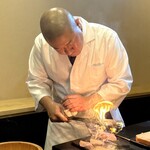 鮨駒 - 熱した鉄串でトロを炙る生駒氏。