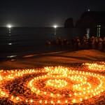金子旅館 - 『波根町の夏の風物詩「キャンドルナイトin波根海岸」でのひとコマ〜日本海の漁火と立神岩の灯台の灯り、そして波根海岸に並ぶロウソクの灯し火（らとちゃん）〜』