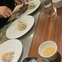 キャトルラパン 北梅田 - サラダと焼かれたステーキを1枚1枚プレートに盛っていく,そして,ドレッシングとステーキソースもかけられる,