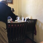 インド料理 パリワル - 片付けが追いついていないテーブル(この日は大盛況！)の食器を手際良く片付けて席に着くおばあちゃん(さすが常連！)