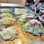 広島風お好み焼き ふみちゃん - キャベツの上にモヤシを乗っけて魚紛的なナニカを振りかけて、豚バラ肉を乗っけてひっくり返し！