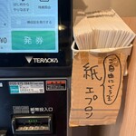 濱虎家 - 食券の販売機横、紙エプロンがあります
