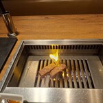 焼肉うしごろ - 鹿児島県産の厚切りサーロインを、網の鉄板で焼いている様子のその3です。少しファイアーダンスの兆候が出ています。