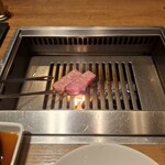 焼肉うしごろ - 鹿児島県産の厚切りサーロインを、網の鉄板で焼いている様子のその1です。