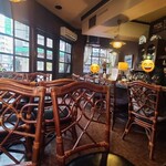 バン - 店内は黄灰色の天井、ガラス張り壁&茶色の柄付き壁、赤茶色の防水シート貼り床、赤紫色な天板テーブル、藤の椅子、茶系の調度品、小さなキッチンでコンパクトな空間、BGMはラジオ音声