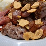 ステーキライスの店 センタービーフ - やわらかめな肉の上にはガーリックチップがずいぶんと！？ただ、意外にも下に潜んでいるガーリックライスのニンニキー感が控えめ？味付けも控えめな感じだったので、カウンター上のステーキソースを投入しました。