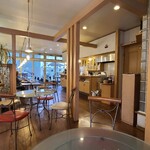 Mugi - 店内はクリーム色の天井、クリーム色の壁、木板張りの床、対面キッチンの様な厨房、電球色のペンダント照明、清潔感もある家庭的な寛ぎの空間、BGM代わりにテレビ音声が流れています