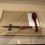 軍鶏拉麺 飛天 - 卓上の木のお盆にセットされた朱塗りのお箸とレンゲ、紙ナプキン