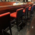 ラトリエ ドゥ ジョエル・ロブション - 赤と黒のモダンな店内、オープンキッチンでカウンターメイン。テーブル数席。