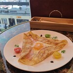 CAFE AUX BACCHANALES - ガレット《ハム》(税込1,230円)
                      ハム&チーズ&半熟玉子&黒胡椒のガレット、削りチーズ掛け、赤&緑&黄のミニ蕃加添え
                      窓から広島電鉄広島電停に路面電車が出入りする様子が眺められます