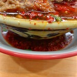 らーめん護什番 - 旨辛痺麺の丼の下に敷いてある受け皿は最初からこんな感じ　丼の縁や側面はスープでベタベタです