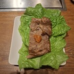 焼肉うしごろ - 網の鉄板の上で焼いた鹿児島県産の大判サーロインを、サムジャンと一緒にサンチュの上にのせた様子です。