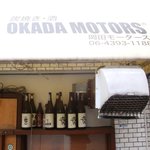 岡田モータース - 意表を突くネーミング、扉の前の焼酎の一升瓶がなければ飲食店とはだれも思いません。