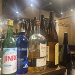 焼酎ダイニング味音 - カウンターにたくさんお酒ならんでる