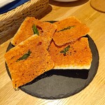 どさんこシェフ イタリアンダイニング - パリパリ食感の自家製チーズクラッカー   軽く食べ進めると焦がしたチーズのコクと旨味がじんわり広がる上質なスナック