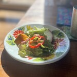 カフェモン - ランチセットのサラダ。カラフルな花柄の皿にレタスやパプリカ、カボチャ、ラディッシュが見えます。クラッシュナッツにオリジナルのドレッシングがおいしい♡