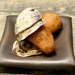 レヴォ - 黒い器に置かれた牡蠣の殻。その中に収まる黄金色のベニエは、まるで海の記憶をそのまま閉じ込めた宝石のようです。富山・入善町の海洋深層水で仕込まれた牡蠣は、薪火で燻されることで香ばしさと海の旨みが凝縮し、さらに油で揚げることで外はカリッと、中はじゅわっと旨みが滲み出します。噛むほどに深い余韻が広がり、潮風の記憶がふと蘇るような感覚に包まれます。