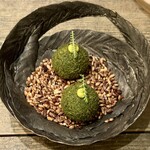 レヴォ - 深い森の奥でひっそりと光る宝石のように、緑の球体が黒い器の中央に佇みます。パセリとパン粉の衣は香ばしく、サクッと軽やかに崩れた瞬間、甘鯛のフィレとじゃがいも、ニンニク、オリーブオイルが一体となった温かな旨味がふわりと広がります。外の香ばしさと中のしっとり感、その対比が心地よく、まるで森の中で焚き火に手をかざすような安堵を覚えます。