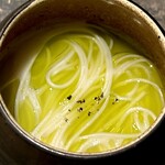 レヴォ - スープは鶏の出汁をベースに山羊のチーズのコクが溶け込んだ乳白色で、香りは穏やかで深い。表面にはふきのとうのオイルが淡い緑の光を差し込み、春の苦みと香りが立ち上がります。器の縁に散らされた黒胡椒が香りに緊張感を添え、土地の特産と季節の兆しが一体となった静謐な構成です。