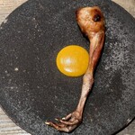 レヴォ - 黒い器の中央に黄金色に焼き上げられた鶏のもも肉が堂々と置かれ、皮目はパリパリと音を立てそうなほど香ばしく、焼き色の陰影が美しい。