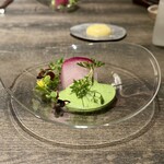 レヴォ - 透明なガラス皿の中央に赤蕪の断面が静かに現れ、腐葉土で固めて塩釜焼きにしたことで表面はわずかに焼き色を帯び、内側は瑞々しく白から紅への美しいグラデーションを描きます。