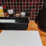 鉄板スパゲッティーズ108 - 卓上の粉チーズなどの調味料と、紙エプロン