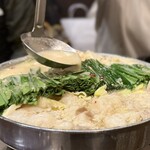 博多もつ鍋 徳永屋 - お玉で出汁をニラにかけ続けます。