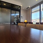 ドトールコーヒーショップ - 店内は白い天井、ガラス張り壁&白と淡灰色のストライプ柄の壁、淡いベージュ色のタイル貼り床、通常のドトールと比べるとやっぱりガソリンスタンドの待合室ぽさが強い空間、BGMは洋楽