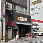 モンク - 外観は「まつぽっくり」さんのある低層ビルの2階にあり、1階の灰色の壁、白い木製開き扉、扉に看板があるだけのシンプルな佇まい、人を寄せ付けないオーラのある佇まい
笠付き裸電球の照明が点灯が営業中の合図