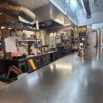 広島鉄板 お好み焼き Re.半田流 - 店内は、サッポロ黒ラベルの横断幕の貼られた白壁、茶色の防水シート貼り床、換気扇フードにLED照明、清掃と整理整頓がなされた清潔感のある空間、BGMはJ-POP
お席はL字鉄板カウンター16席