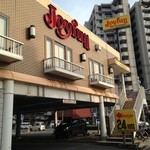 ジョイフル - 外観。交差点の角にあり、２方向からの出入りが可能。１階部分が専用駐車場（有料）