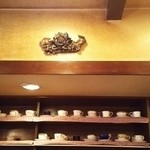 くらもち珈琲 - 壁のカップ棚の上のモニュメント