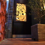 BRILLANTE IL SUZUKI - 階段を上り、オリーブの木の先にアイアンアートが施されたダークブラウンの木の扉が入口