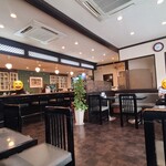 矢馬野 - 店内は白い天井、ガラス張り壁&複数の絵画が飾られた白壁、厨房は緑色のタイル貼り壁、灰紫色のタイル貼り床、ダウンライトの照明、清潔感があり、落ち着いた純喫茶らしい空間、BGM代わりのTV音声