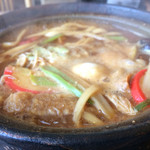 丸岡うどん - 丸岡うどん・グツグツと土鍋で煮え立つ具沢山の味噌煮込みうどん
      真ん中に生卵が落とされている。