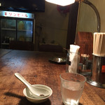 ICHI - 2015年6月上旬 木のテーブル&ライト&灰皿&割り箸&ナプキン&お冷&黒ダレ。奥に古い冷蔵庫キリンビール照明が綺麗で良い雰囲気です。