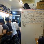 釜谷 - 少し右に振りました。右側はテーブル席になっているんですよ。狭い店内ですが上手に工夫して沢山の人が座れるようになっています。目の前になりやらボードがありますね。